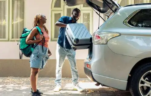 Voyageurs avec valises à côté d'une voiture de transfert